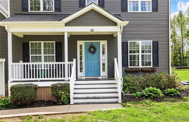 view of exterior entry featuring covered porch and roof with shingles