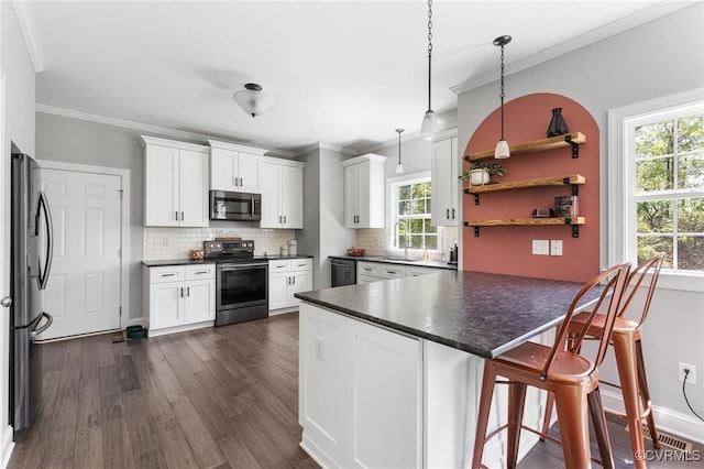 kitchen with white cabinets, backsplash, dark countertops, a sink, and appliances with stainless steel finishes