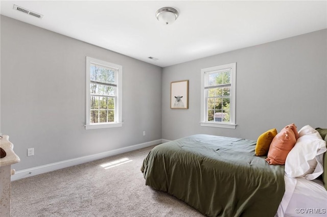bedroom featuring carpet floors, visible vents, baseboards, and multiple windows