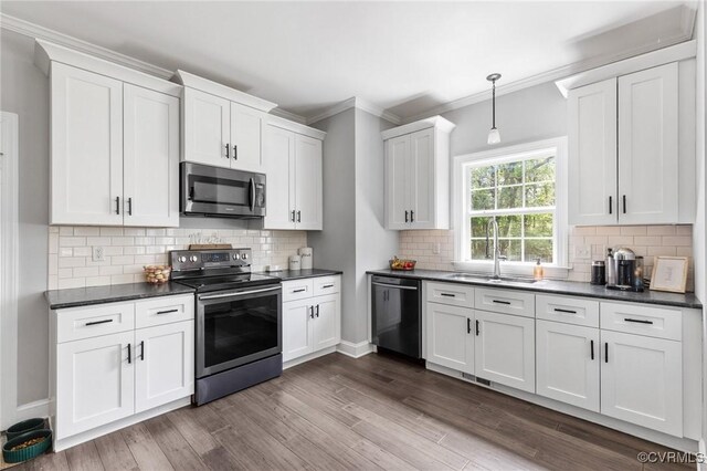 kitchen featuring dark countertops, appliances with stainless steel finishes, ornamental molding, and a sink