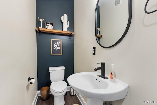 bathroom featuring toilet, wood finished floors, a sink, baseboards, and visible vents