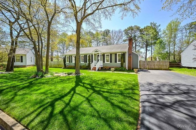 view of front of house featuring a front yard, driveway, fence, and a chimney