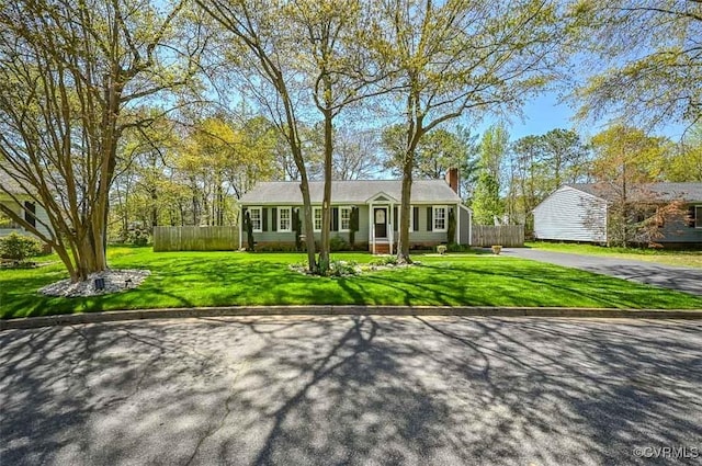 view of front of home featuring a chimney, fence, a front yard, and driveway
