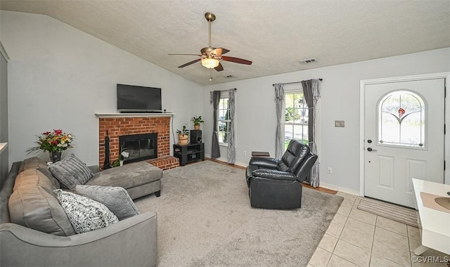 living room with lofted ceiling, light tile patterned floors, ceiling fan, visible vents, and a fireplace