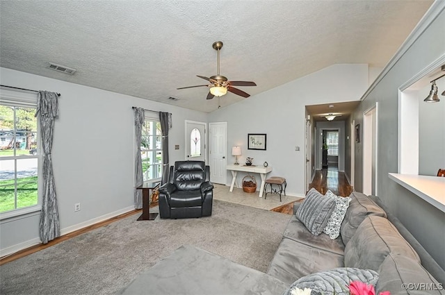 living area featuring a textured ceiling, visible vents, a ceiling fan, and vaulted ceiling