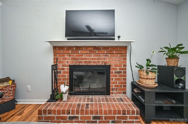 interior details featuring wood finished floors, baseboards, and a brick fireplace