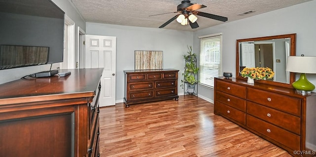 bedroom featuring a textured ceiling, visible vents, light wood finished floors, and baseboards