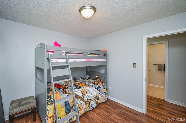 bedroom featuring a textured ceiling, wood finished floors, and baseboards
