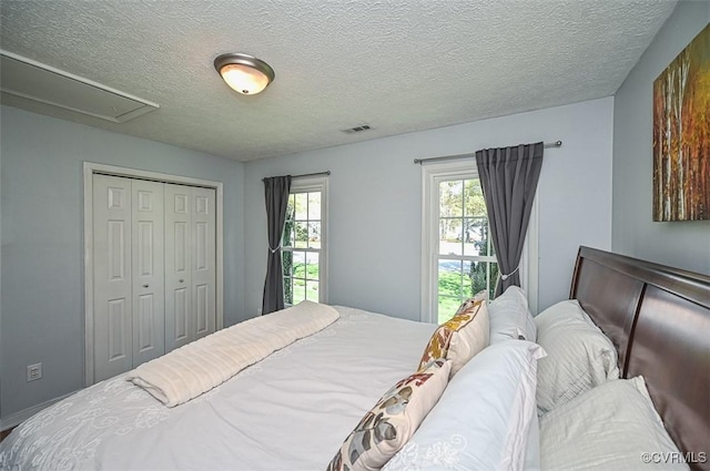 bedroom featuring visible vents, a textured ceiling, and a closet