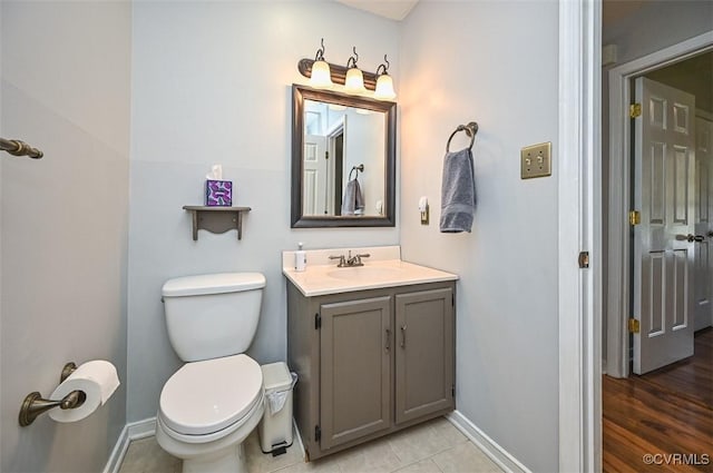 half bathroom featuring vanity, toilet, tile patterned flooring, and baseboards