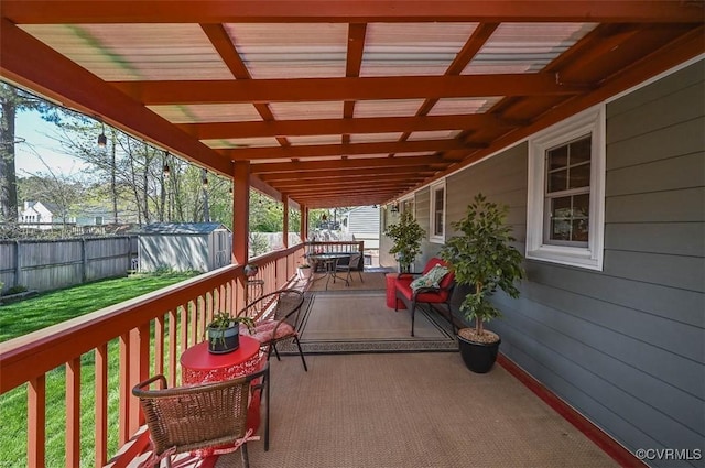 deck with an outbuilding, a fenced backyard, a shed, a lawn, and outdoor dining space