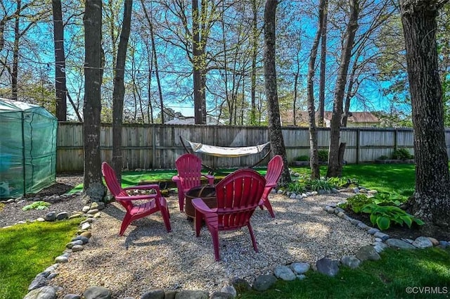 view of yard with a fire pit, a fenced backyard, and a greenhouse