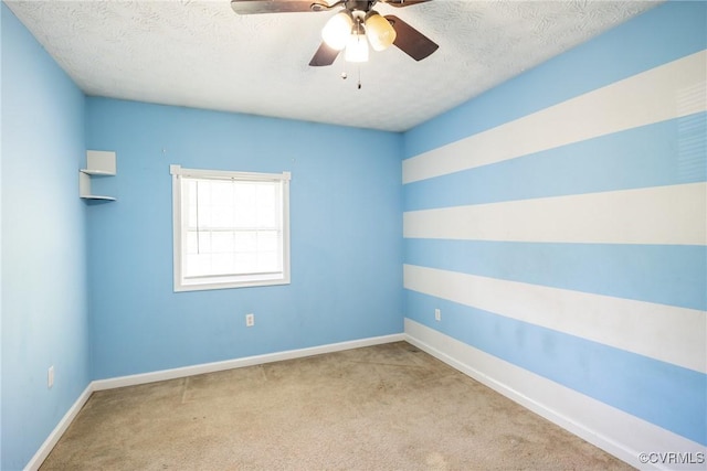 carpeted spare room with baseboards, a textured ceiling, and ceiling fan