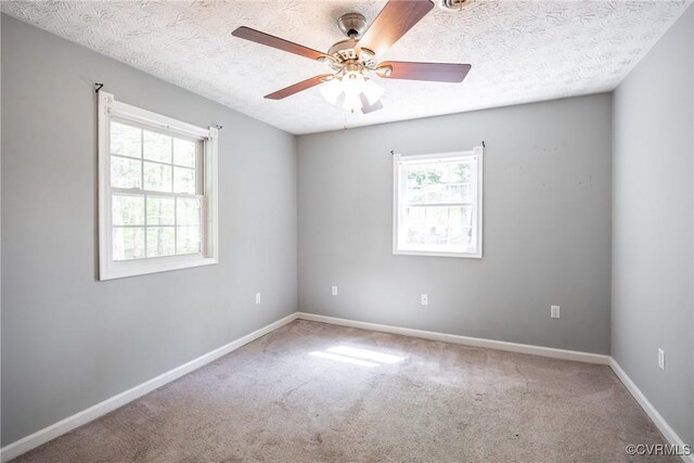 spare room featuring baseboards, a ceiling fan, a textured ceiling, and carpet