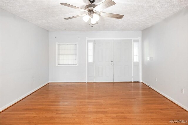 unfurnished bedroom with a textured ceiling, light wood-type flooring, baseboards, a ceiling fan, and a closet