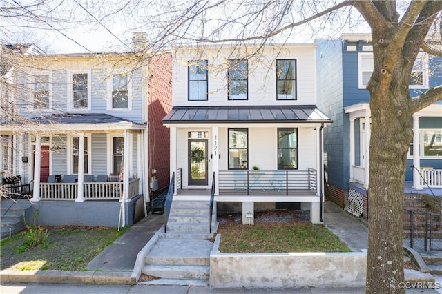 townhome / multi-family property with a chimney, covered porch, a standing seam roof, and metal roof