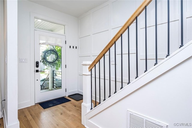 foyer featuring visible vents, stairway, and wood-type flooring