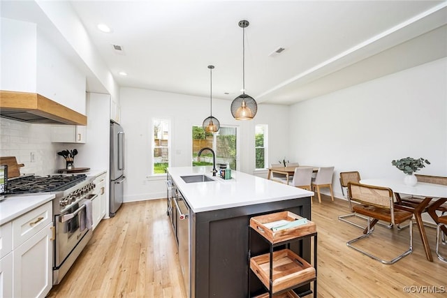 kitchen with a sink, stainless steel appliances, custom range hood, white cabinets, and visible vents