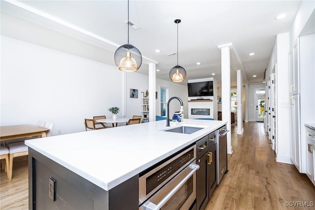kitchen with light countertops, a sink, a kitchen island with sink, and recessed lighting