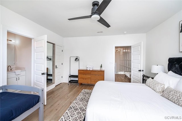bedroom featuring light wood-style flooring, a sink, ensuite bathroom, and a ceiling fan