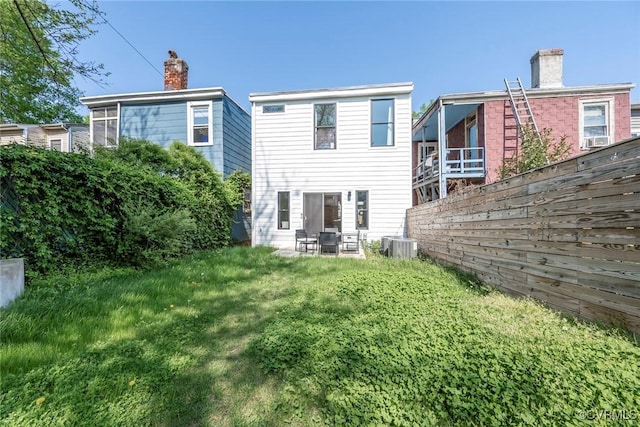 rear view of house featuring central air condition unit, fence, and a yard