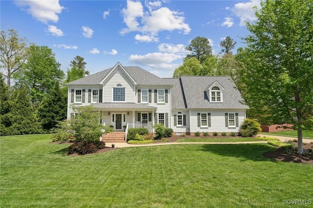colonial inspired home with a porch, roof with shingles, and a front yard