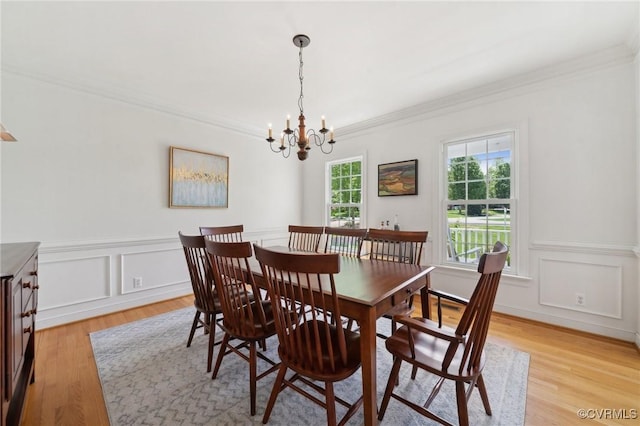 dining area featuring an inviting chandelier, ornamental molding, light wood-style floors, and wainscoting