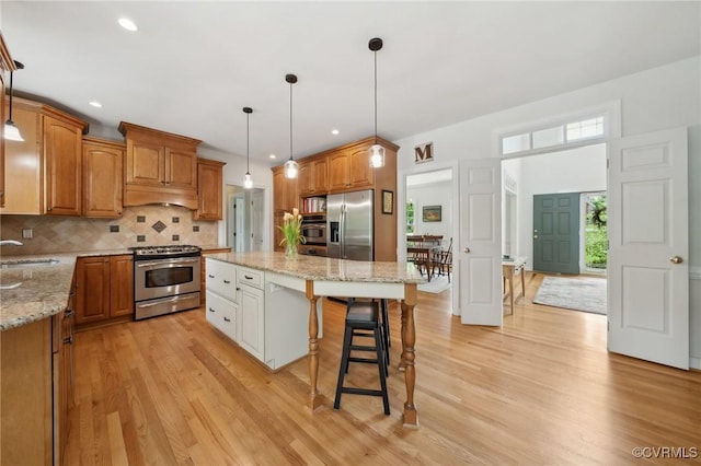 kitchen featuring appliances with stainless steel finishes, a breakfast bar, light stone counters, tasteful backsplash, and a kitchen island
