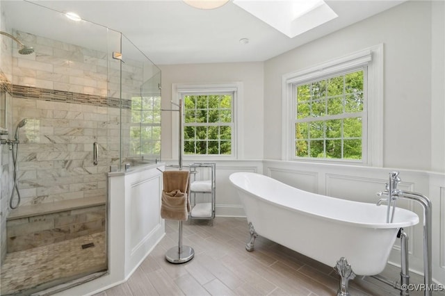 full bathroom featuring a freestanding tub, a stall shower, a healthy amount of sunlight, and a skylight