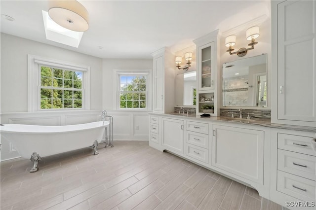 bathroom featuring a freestanding bath, wainscoting, wood finished floors, a sink, and a decorative wall