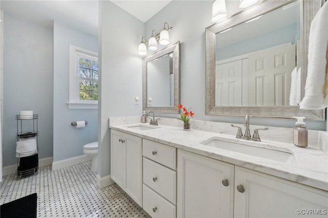 full bathroom featuring baseboards, a sink, double vanity, and toilet