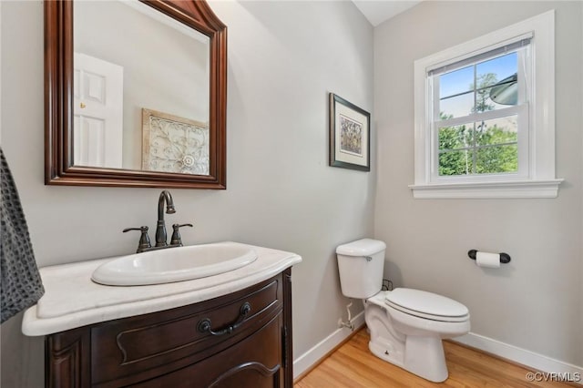 bathroom with baseboards, wood finished floors, toilet, and vanity