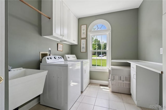 laundry area featuring washing machine and clothes dryer, cabinet space, a sink, baseboards, and light tile patterned flooring
