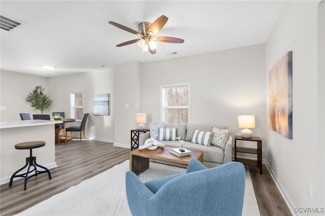 living room with wood finished floors, baseboards, a ceiling fan, and visible vents