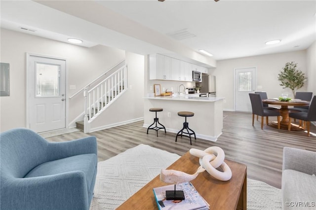 living area with visible vents, baseboards, stairway, and light wood-style floors