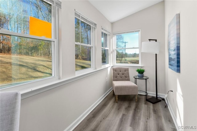 living area featuring baseboards, vaulted ceiling, and wood finished floors
