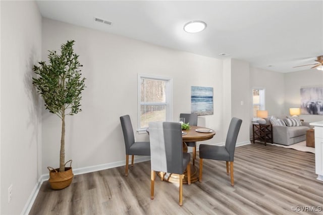 dining room with light wood-style floors, plenty of natural light, visible vents, and baseboards