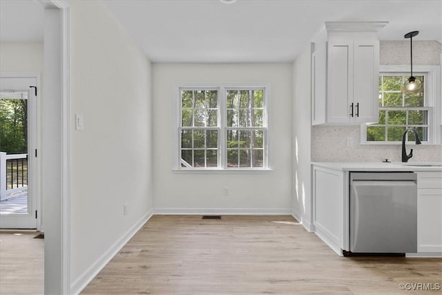 bar featuring baseboards, light wood-type flooring, tasteful backsplash, a sink, and dishwasher