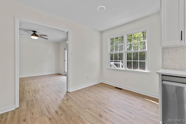 unfurnished dining area with a ceiling fan, baseboards, visible vents, and light wood-style flooring