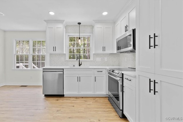 kitchen with a sink, light countertops, stainless steel appliances, white cabinetry, and decorative backsplash