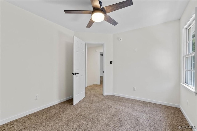 empty room featuring a ceiling fan, baseboards, and light colored carpet