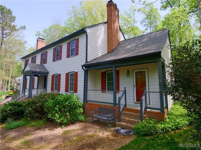 colonial inspired home featuring a porch and a chimney