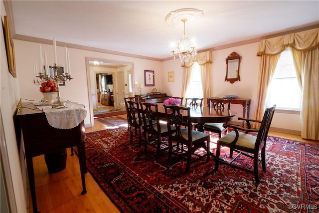 dining space featuring ornamental molding, wood finished floors, and a notable chandelier