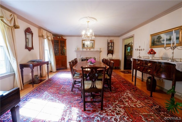 dining area with a healthy amount of sunlight, ornamental molding, wood finished floors, and a chandelier