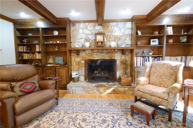 living area featuring ornamental molding, a fireplace, beam ceiling, and wood finished floors