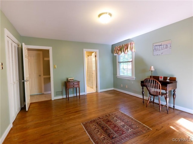 sitting room with baseboards, wood finished floors, and visible vents