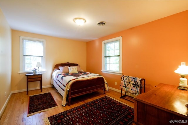 bedroom with visible vents, baseboards, and wood finished floors