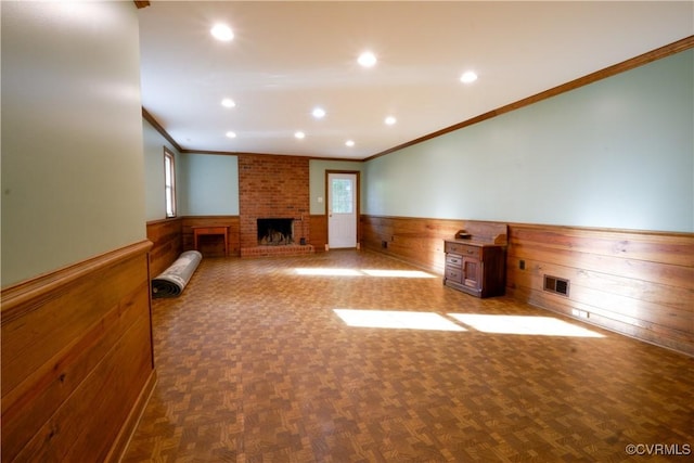 unfurnished living room featuring wooden walls, a wainscoted wall, recessed lighting, visible vents, and ornamental molding