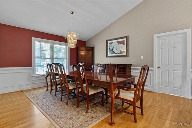 dining room with a notable chandelier, a wainscoted wall, lofted ceiling, and light wood-style floors