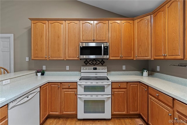 kitchen featuring light countertops, vaulted ceiling, and white appliances